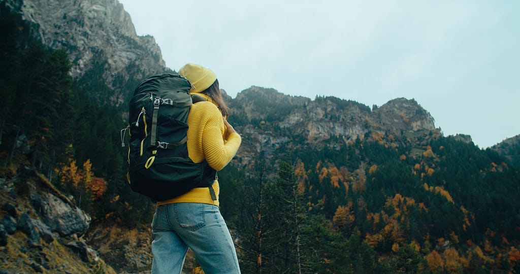 Backpacker tourist stand on mountain landscape at autumn travel on cloudy day Traveling solo