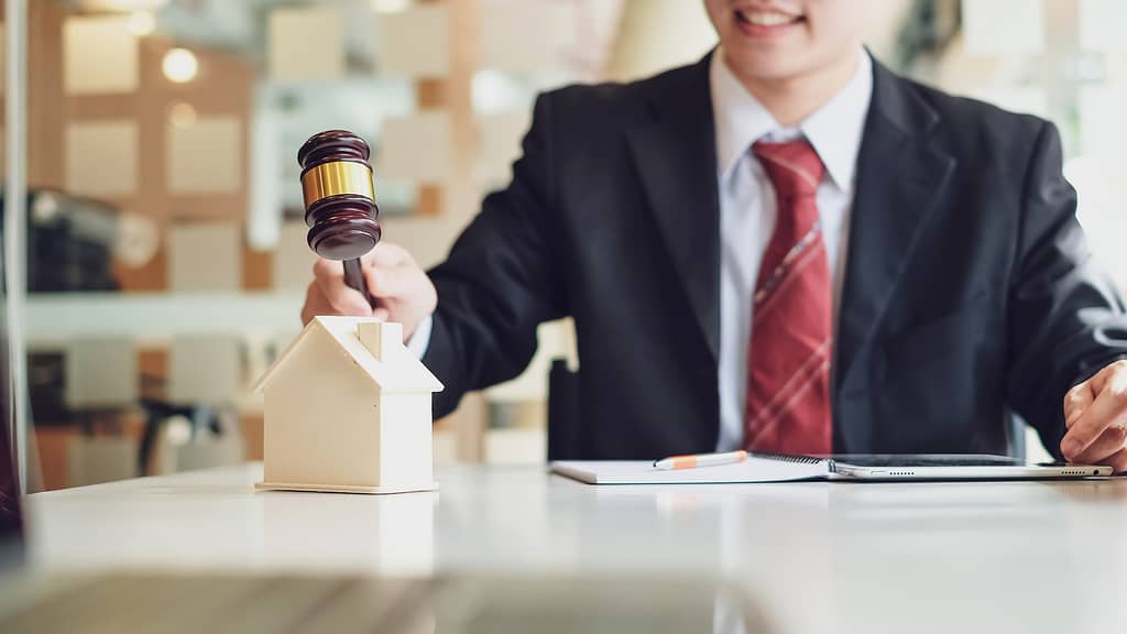 Close-up of lawyer hand holding real estate hammer house and building idea at the office.